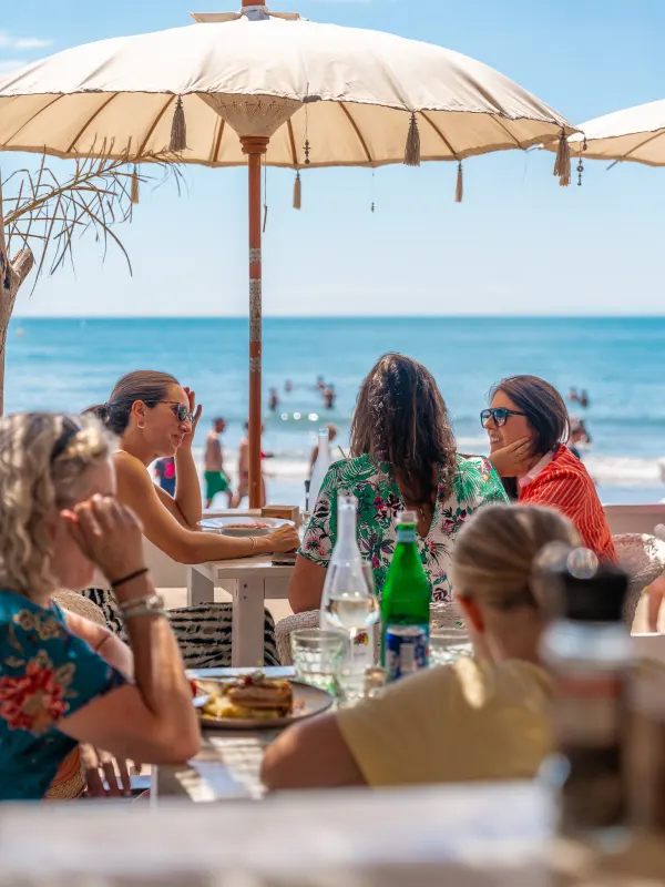 Déjeuner entre amies sous le parasol, vue sur la mer