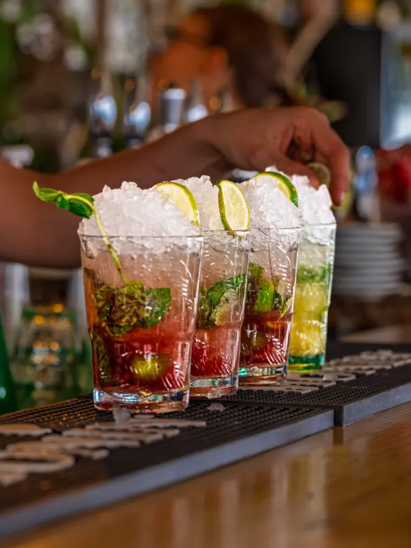 Préparation des mojitos au bar : citron vert, menthe et glace pilée